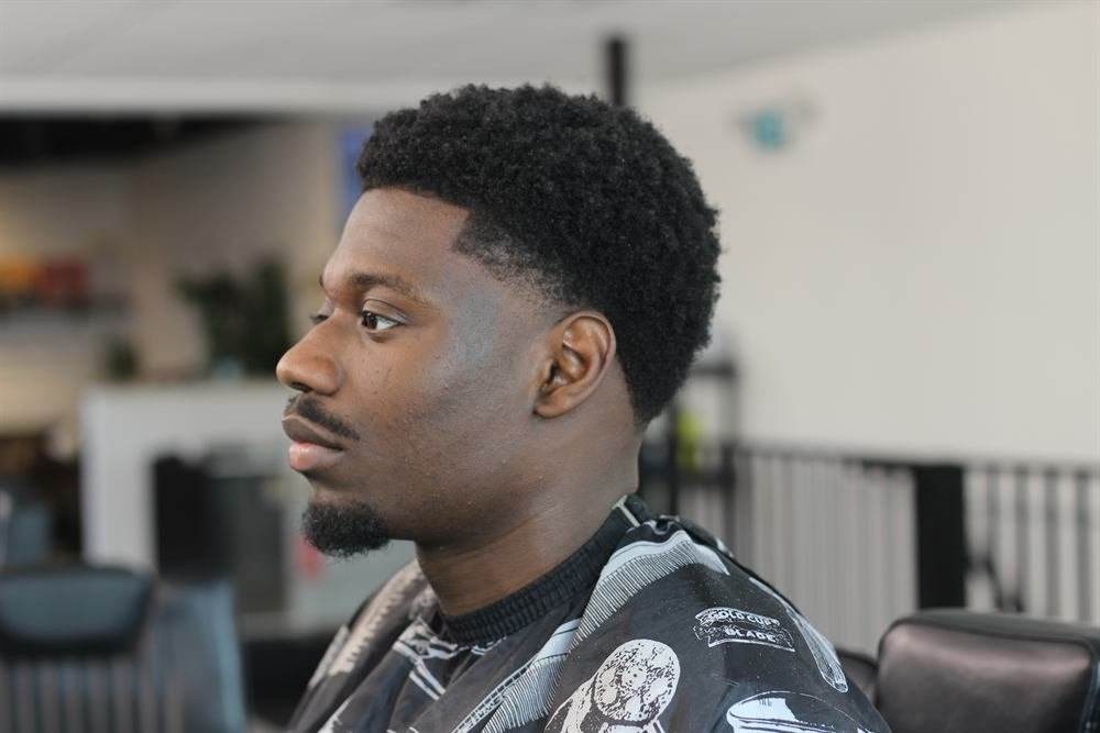 Side profile of a sharp curly top with a crisp line-up