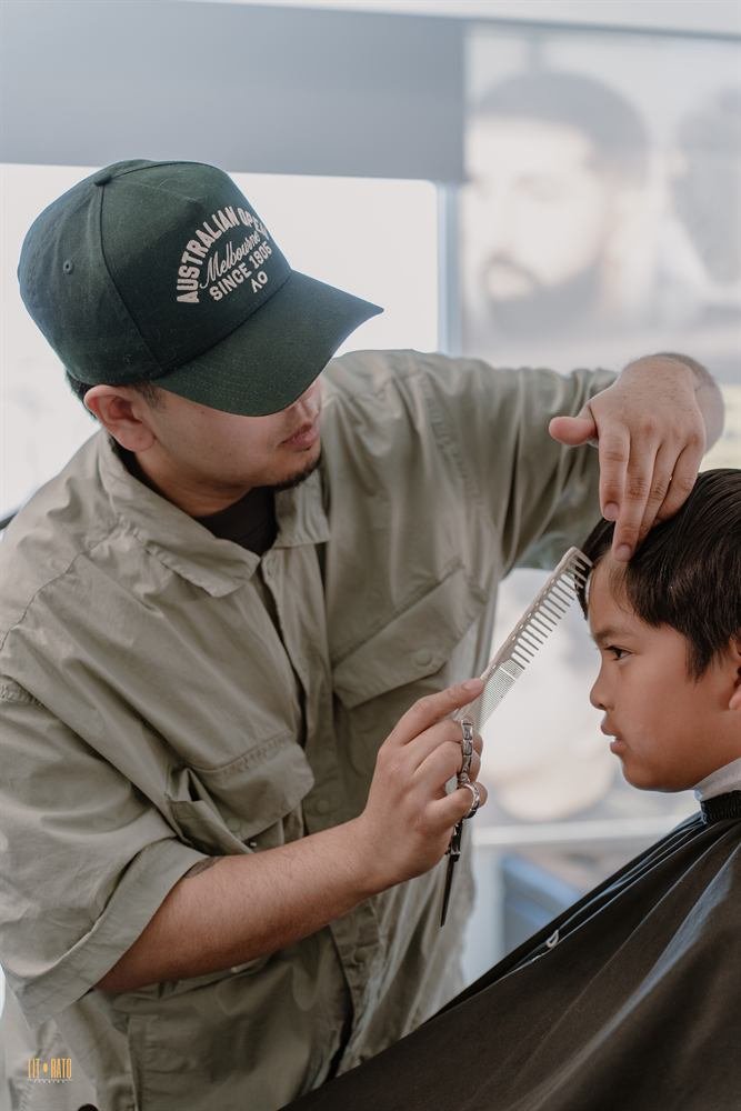 Barber detailing a client's cut with scissors and comb