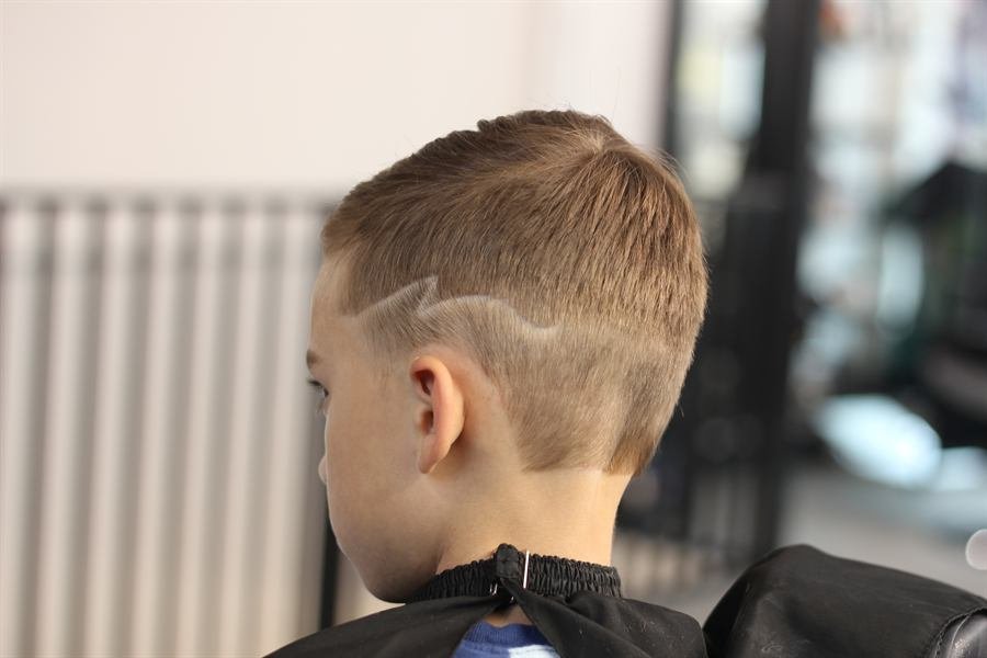Young boy showing off a fresh fade with a line design