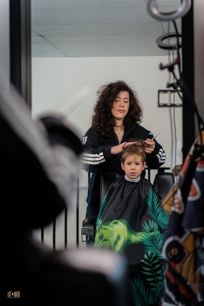 A stylist cutting a young boy's hair in the barber chair
