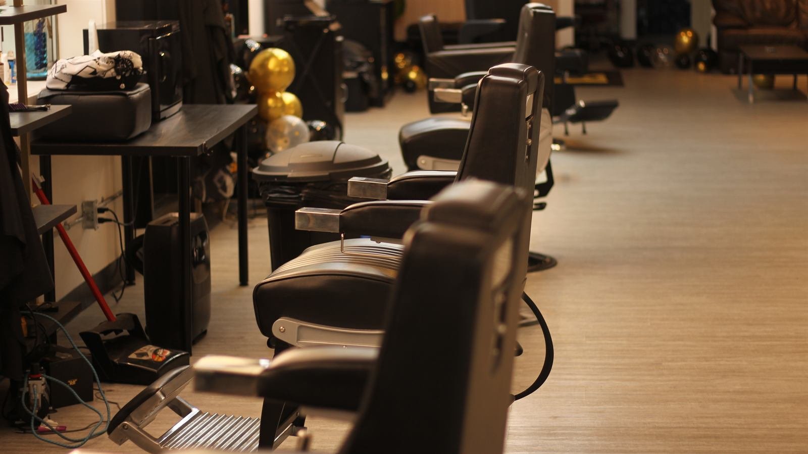 Row of black leather barber chairs inside the bright Dream Barbers shop